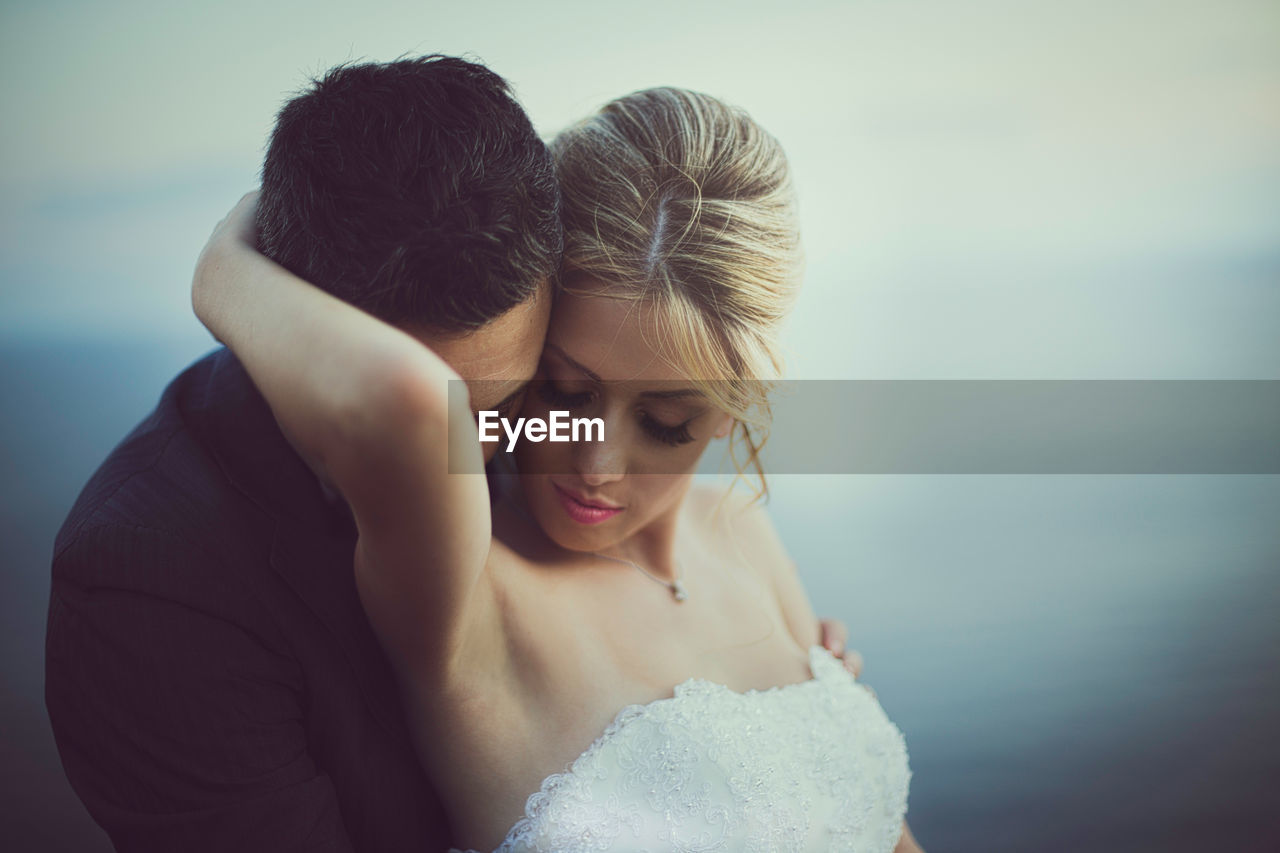 Midsection of couple kissing against sea