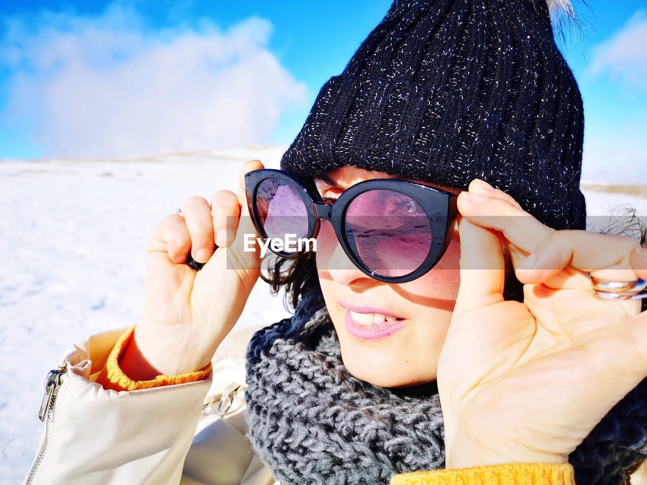 Woman in wool hat takes off sunglasses in the mountains