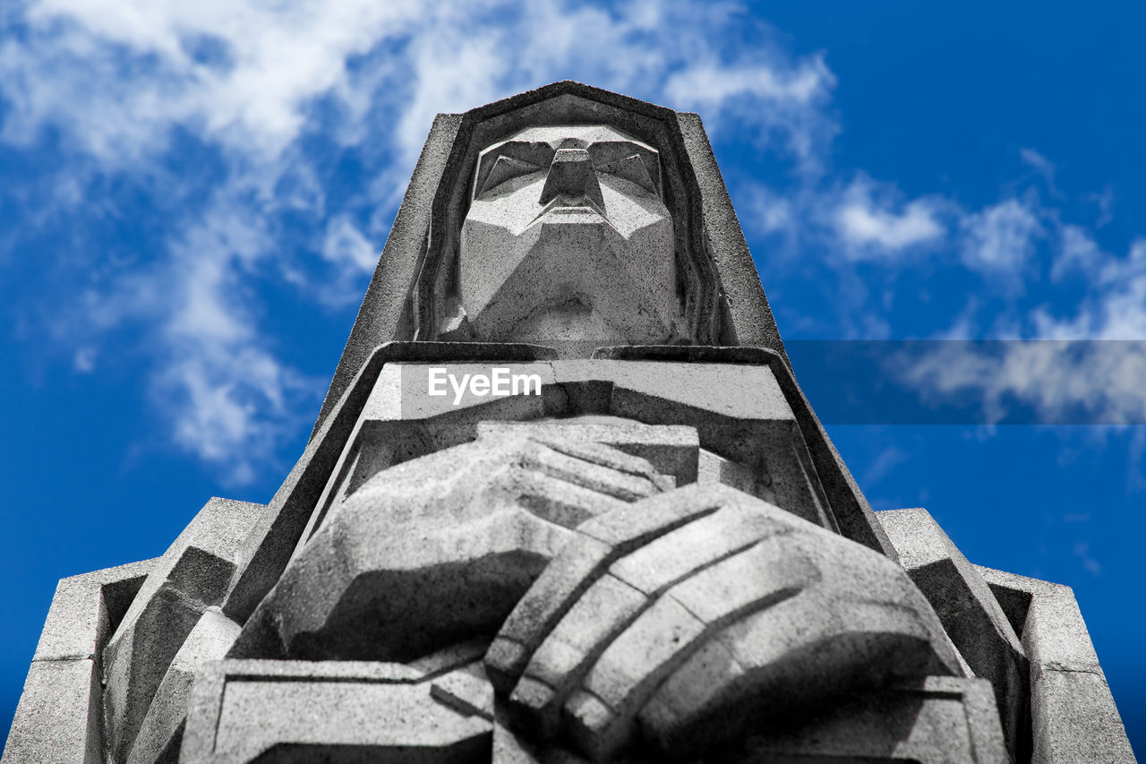 Low angle view of statue against blue sky during sunny day