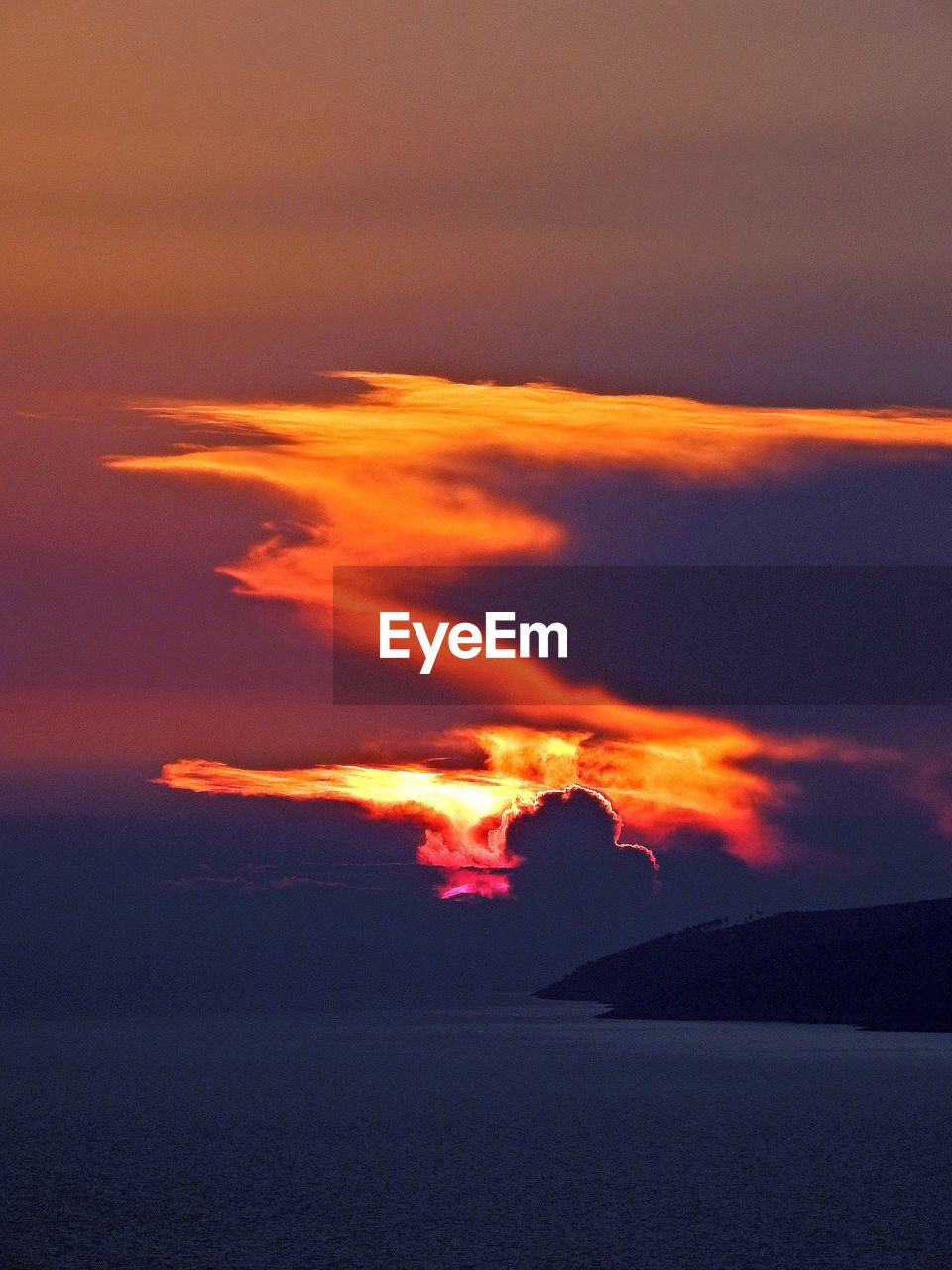 SCENIC VIEW OF SEA AND SILHOUETTE MOUNTAIN AGAINST ORANGE SKY