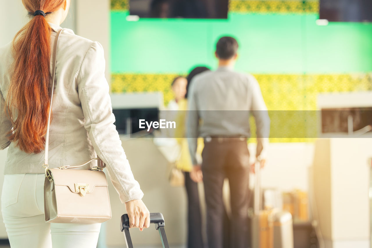 At the airport check-in counter, a passenger hands over his documents to the manager via a counter 