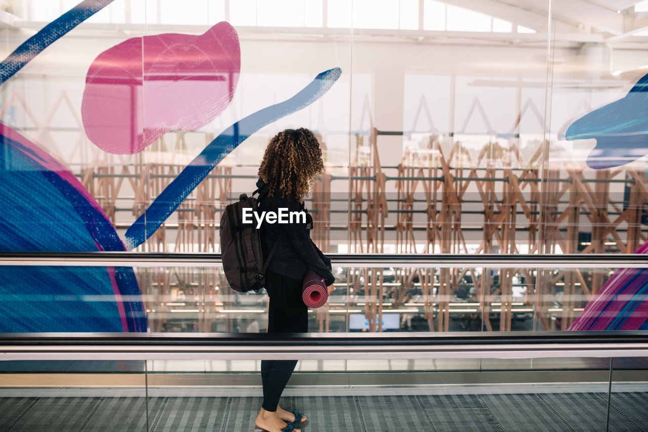 REAR VIEW OF WOMAN STANDING ON RAILING