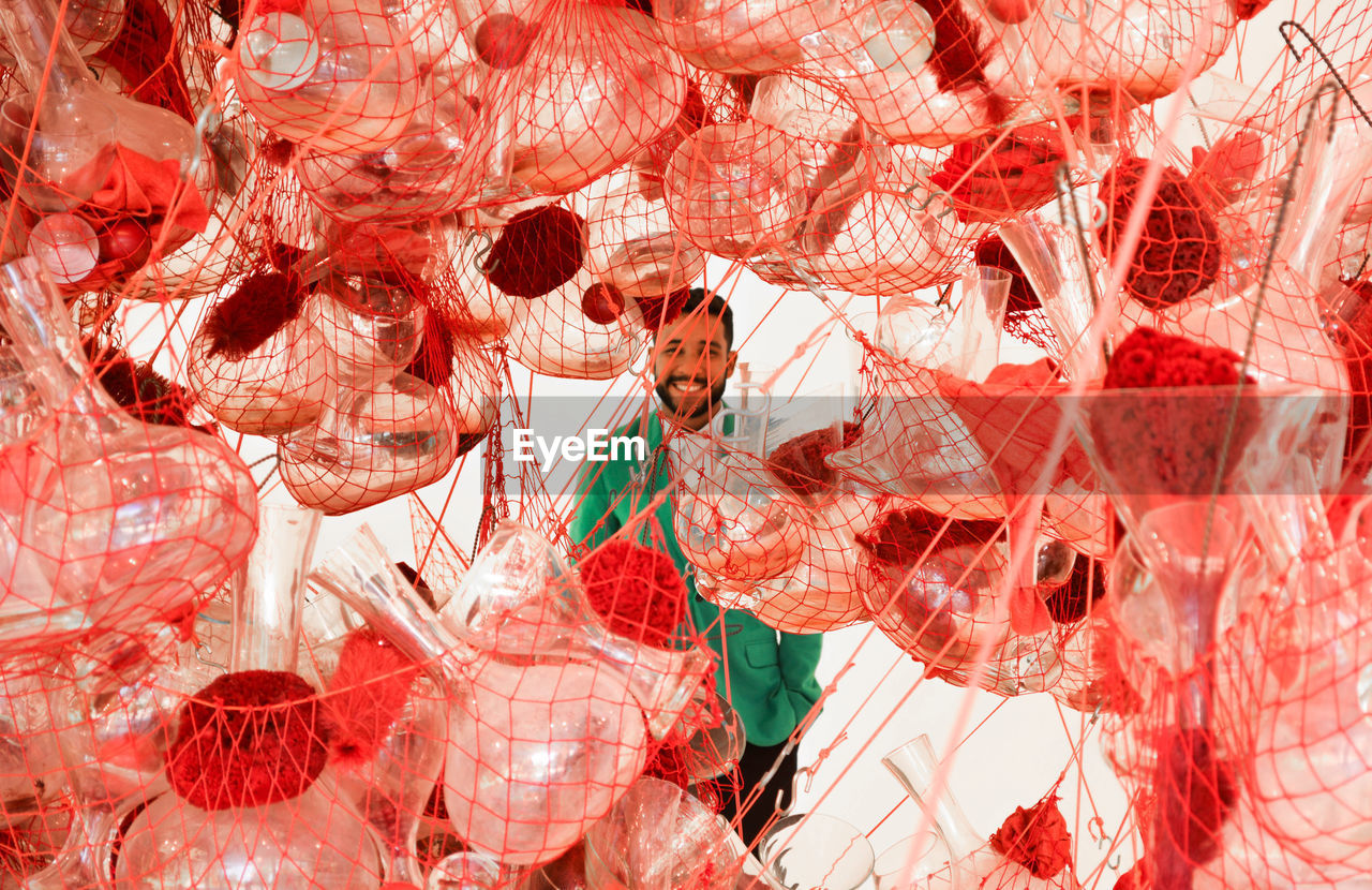 Bottles and containers in net with smiling man standing in background