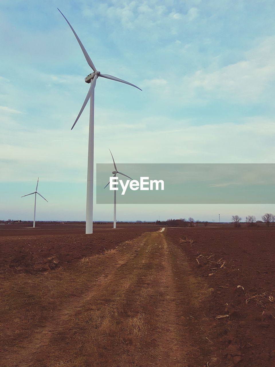 WIND TURBINES ON FIELD AGAINST SKY