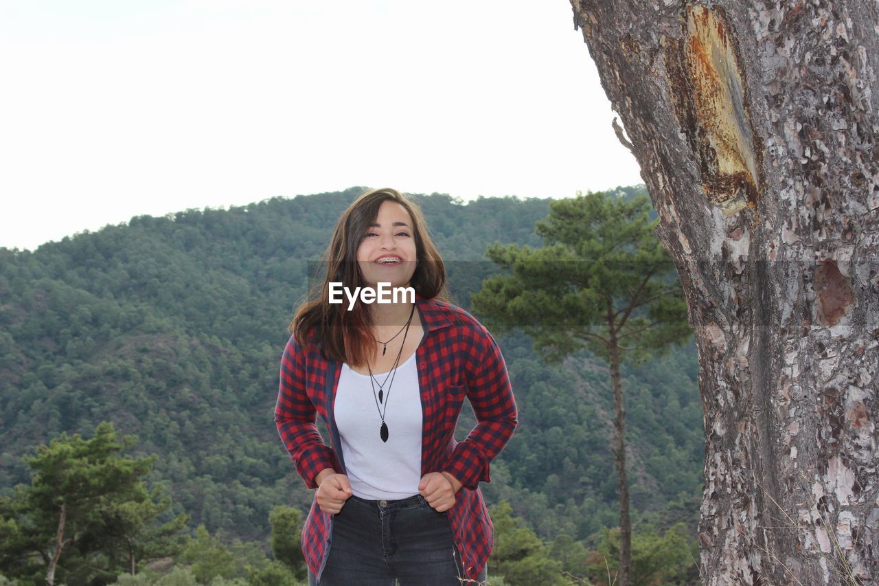 Portrait of smiling woman standing against mountains