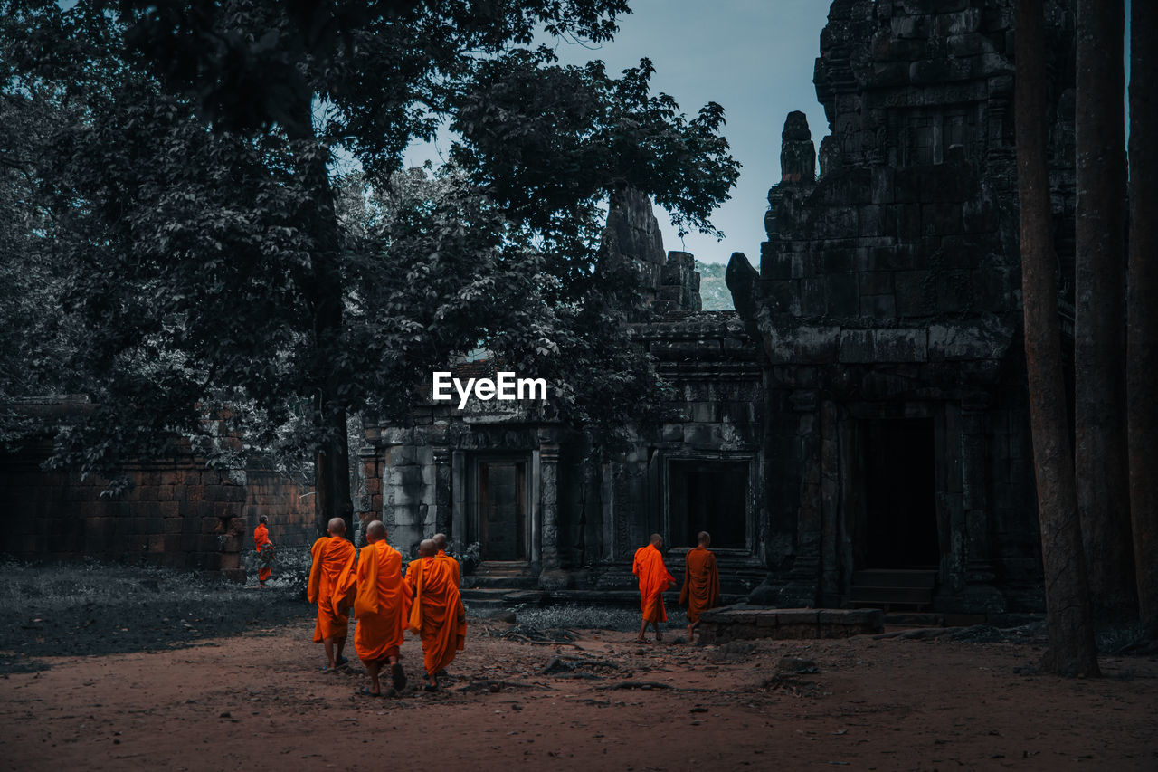 GROUP OF PEOPLE BY TREE OUTSIDE BUILDING