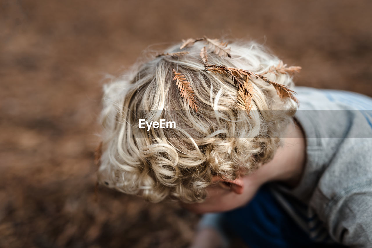 Pine needle leaves on head of curly haired child