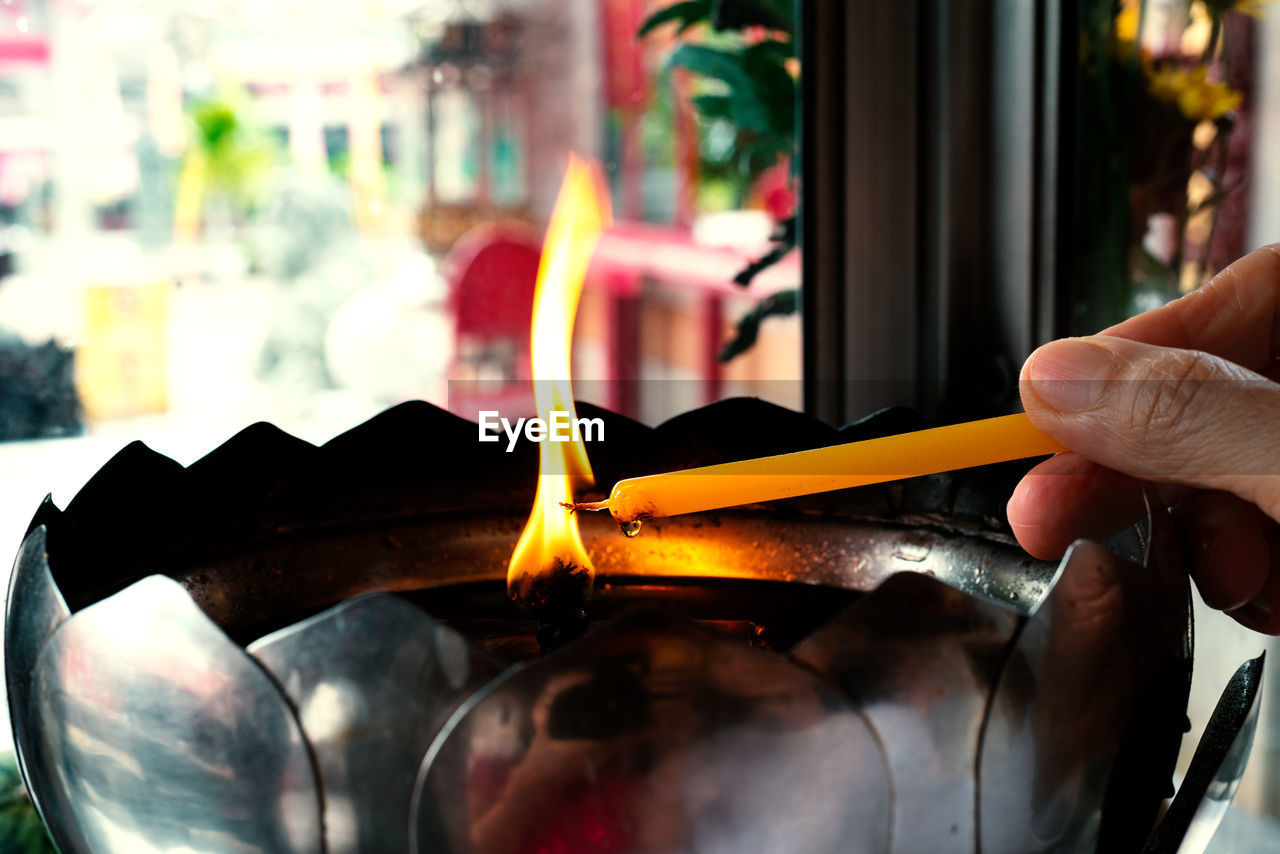 CLOSE-UP OF HAND HOLDING LIT CANDLE