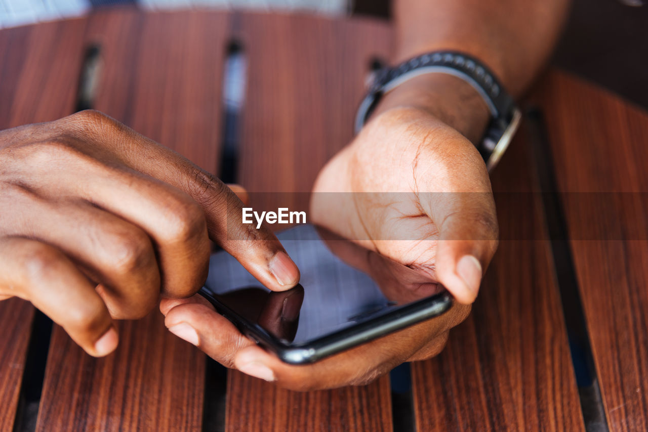 Close-up of man using mobile phone on table