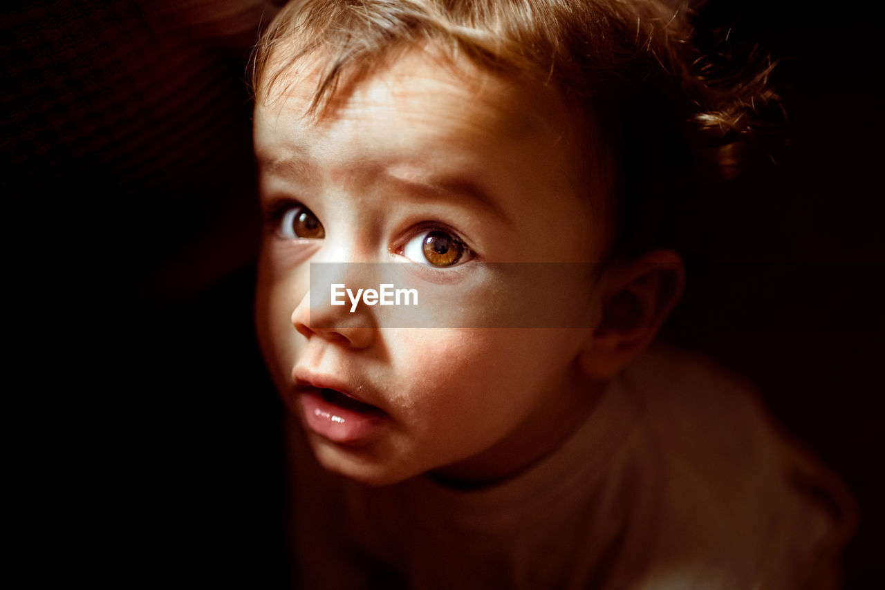 Close-up portrait of cute baby girl against black background