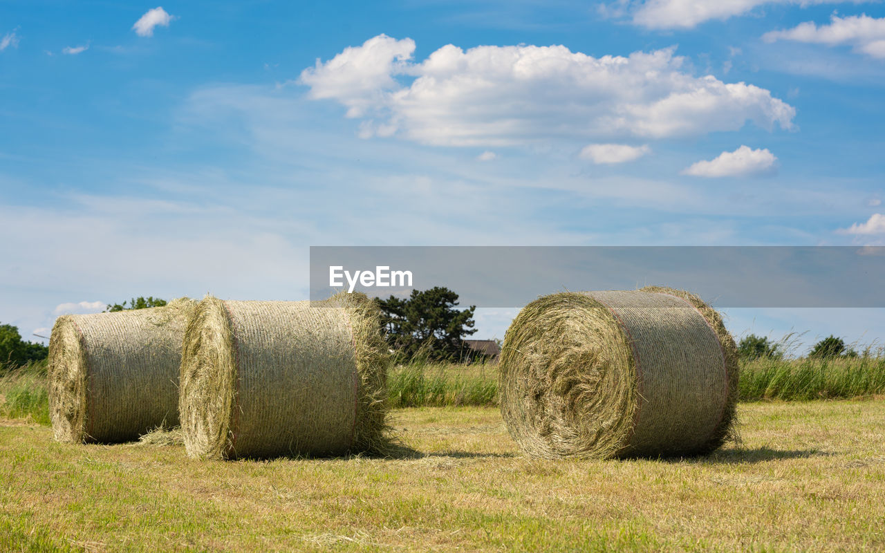 HAY BALES ON FIELD AGAINST SKY AT SUNSET