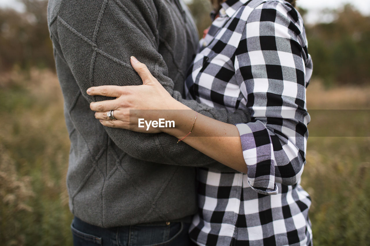 Midsection of romantic couple embracing while standing in forest