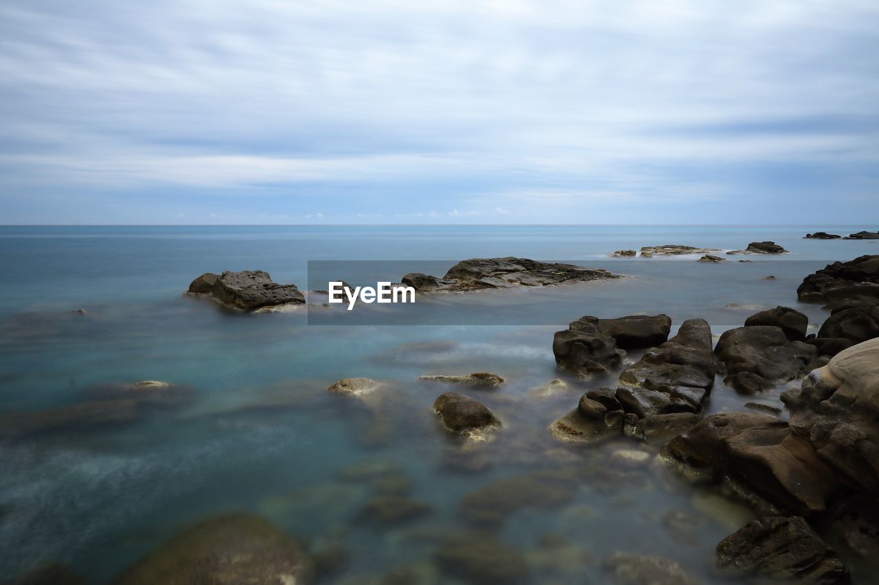 SCENIC VIEW OF ROCKS ON SEA AGAINST SKY