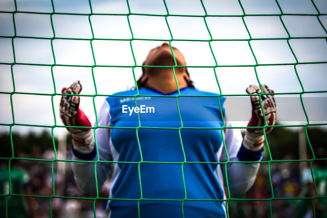 Low angle view of woman seen through net at soccer field