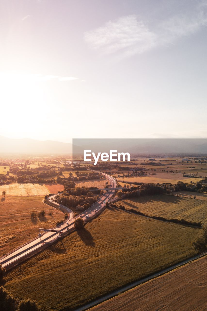 High angle view of country road amidst farms against sky