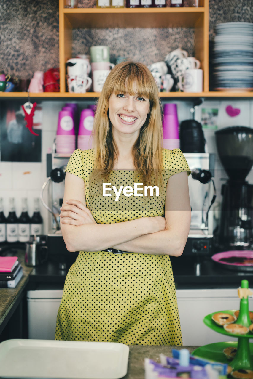 Portrait of confident barista standing arms crossed in cafe