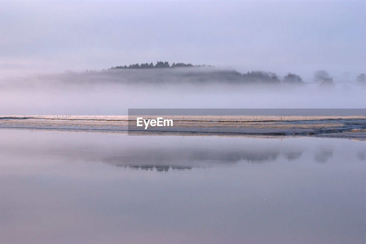 Scenic view of lake against sky during winter