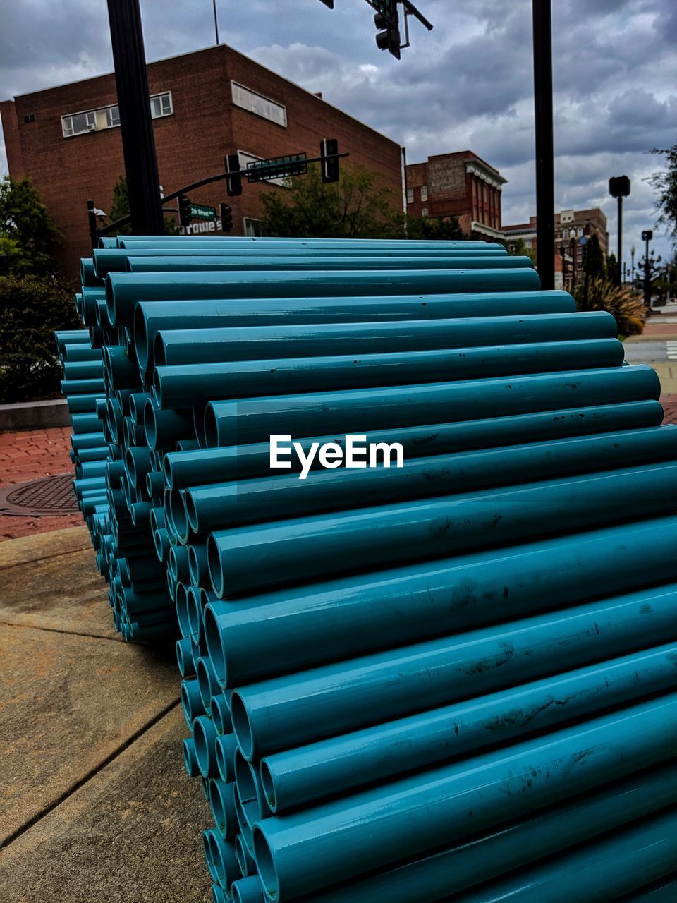 Stack of pipes on street against buildings