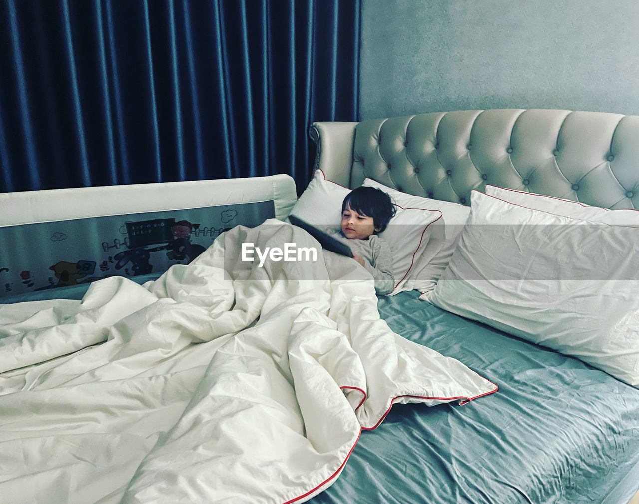 Midsection of boy resting on bed at home