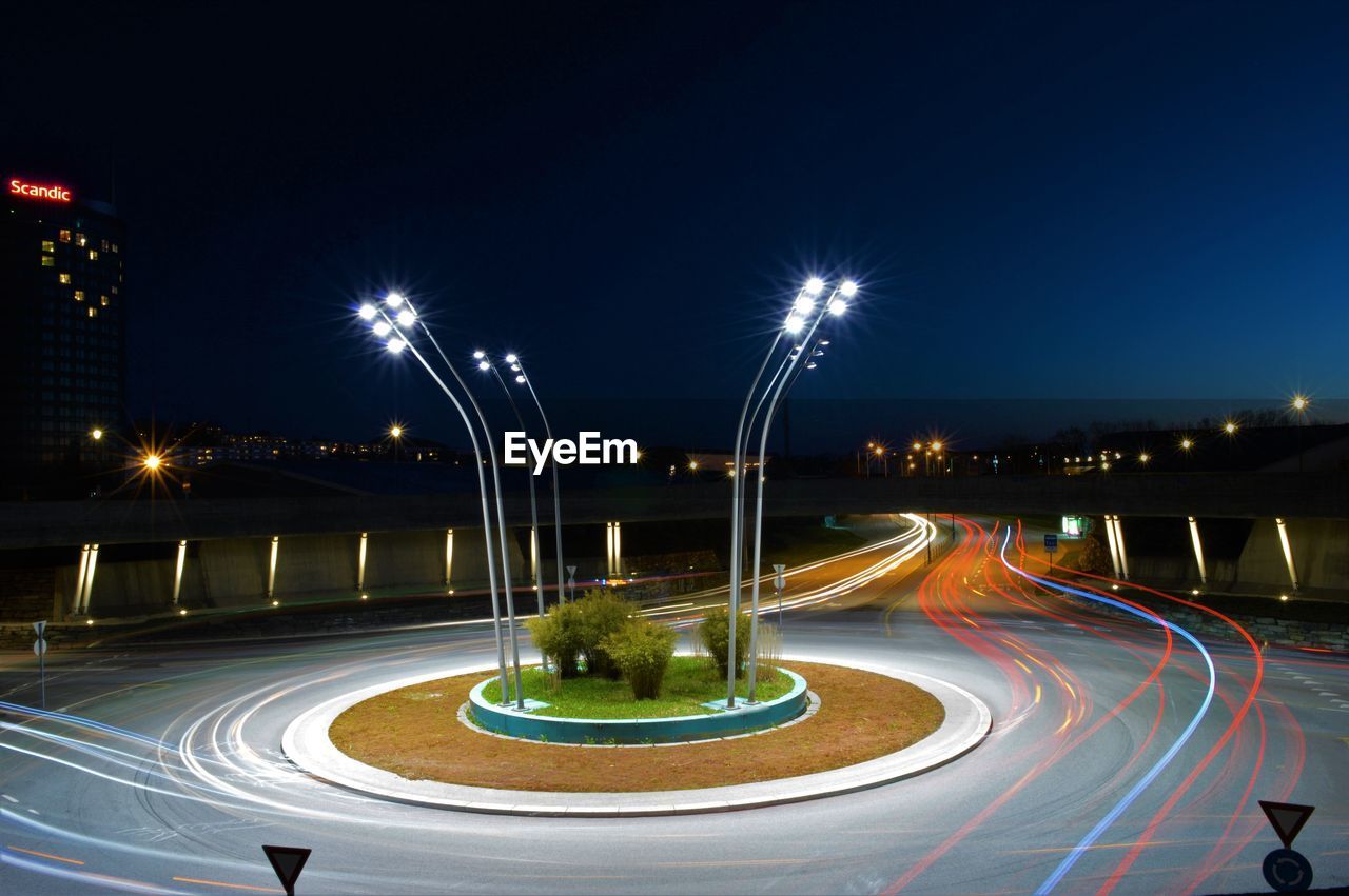 Light trails on street against sky at night