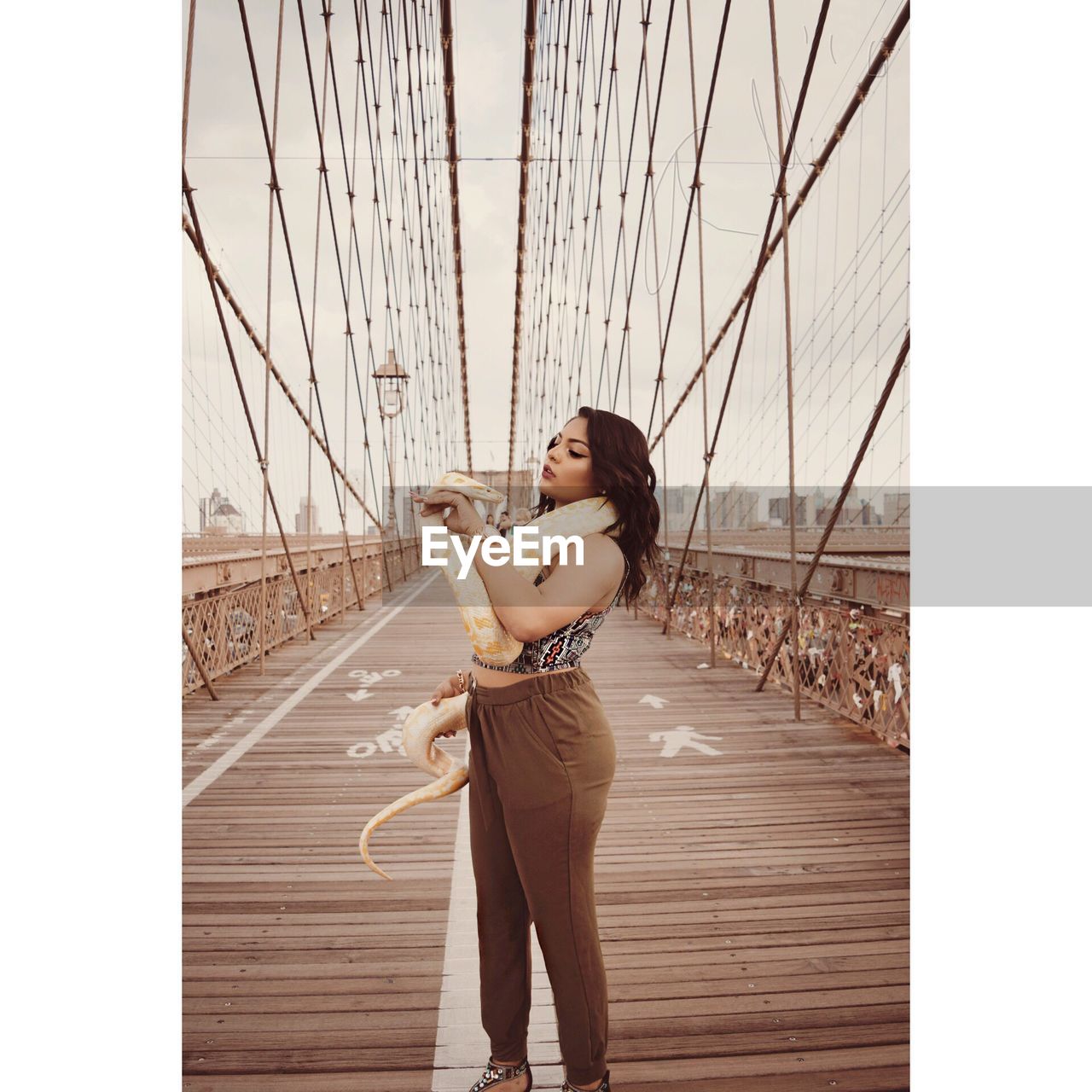 Young woman holding snake on brooklyn bridge