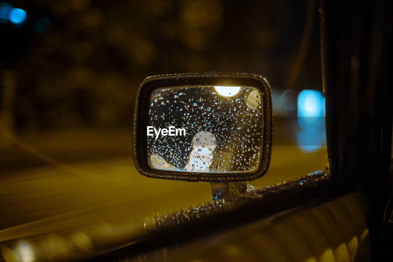 Raindrops on side-view mirror of car at night
