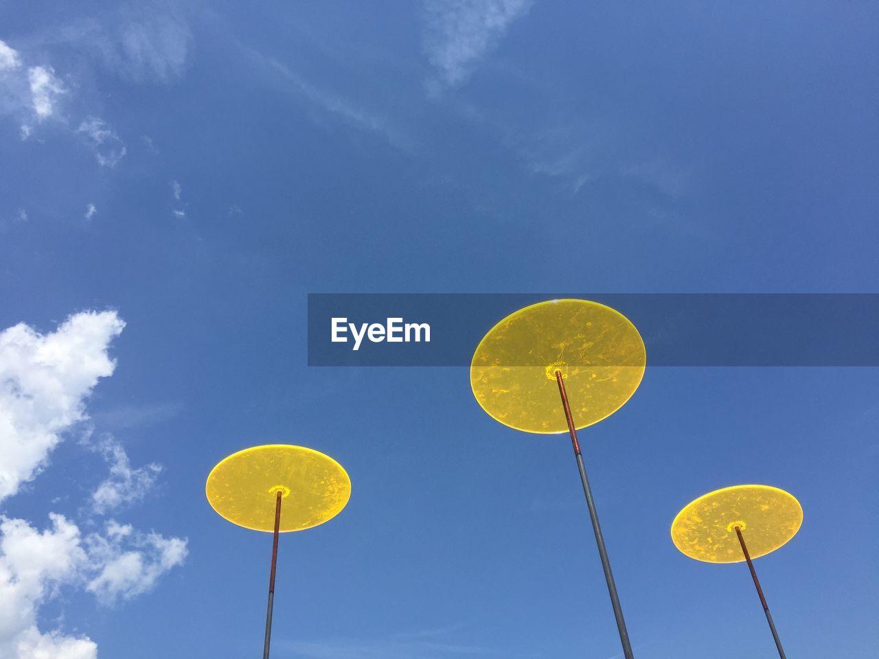 Low angle view of yellow decorations against blue sky