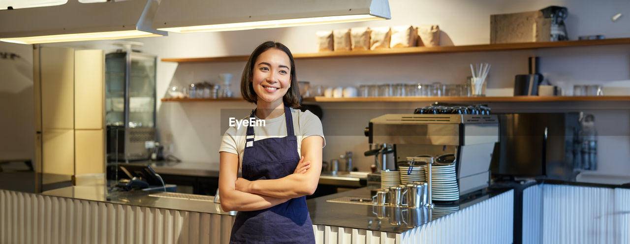 portrait of smiling young woman standing in kitchen