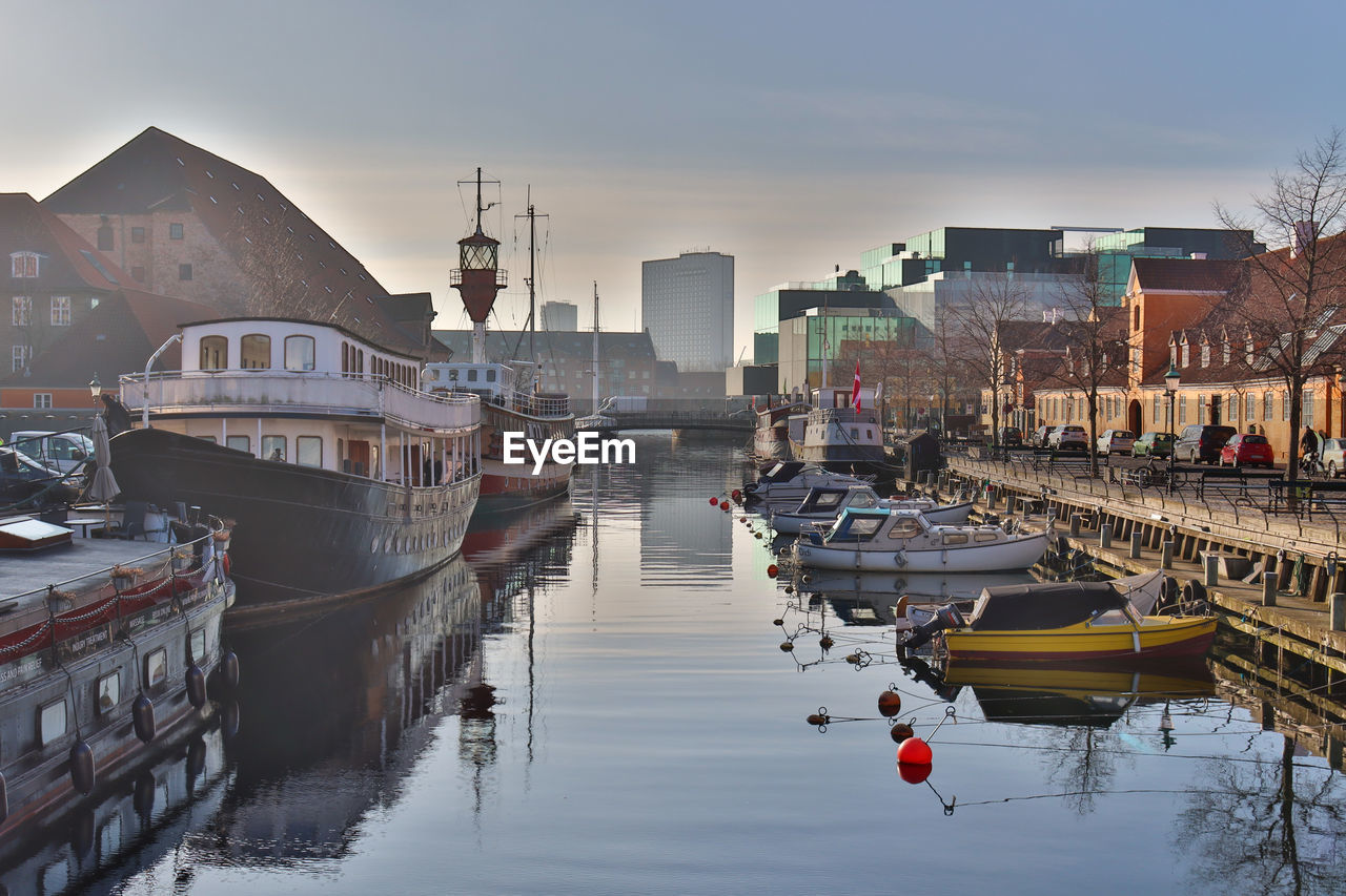 Boats moored at harbor by buildings in city