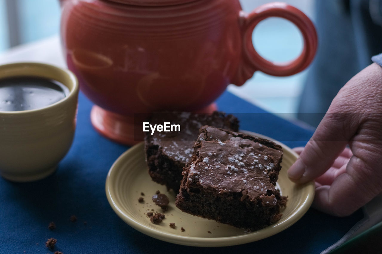 Close-up of hand holding dessert served on table