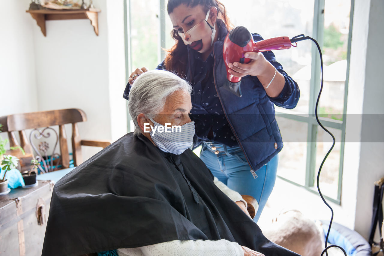 Beautician treating hair of customer at home