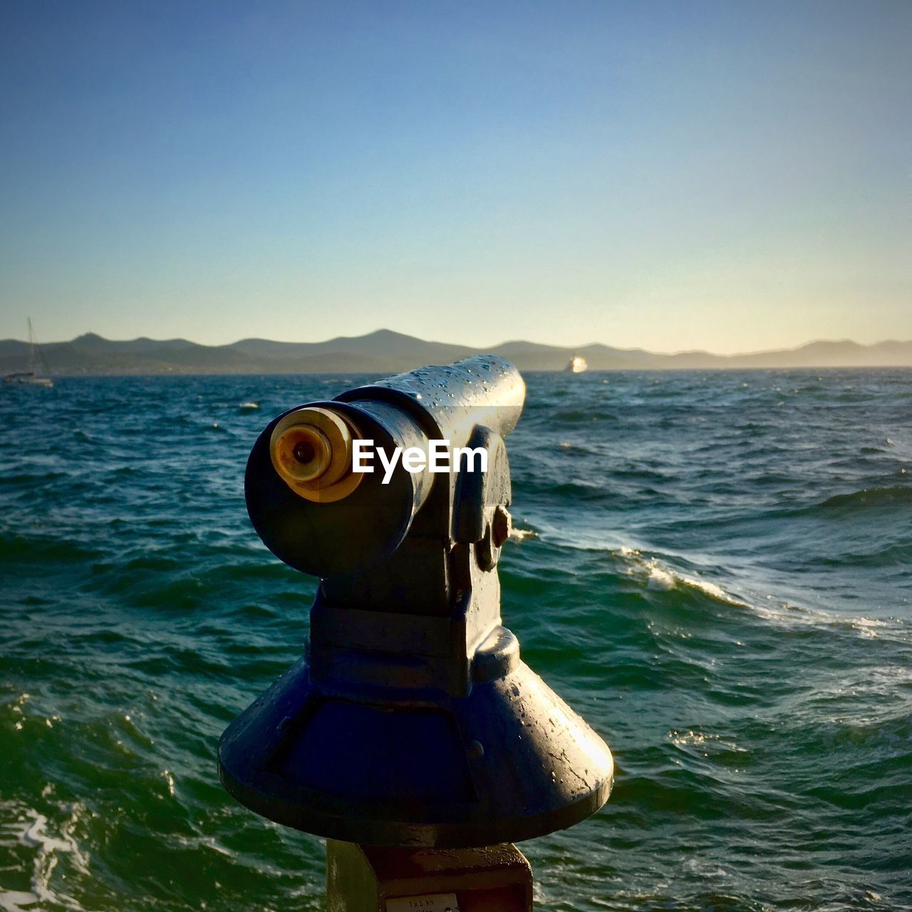 Coin operated telescope on sea against clear sky