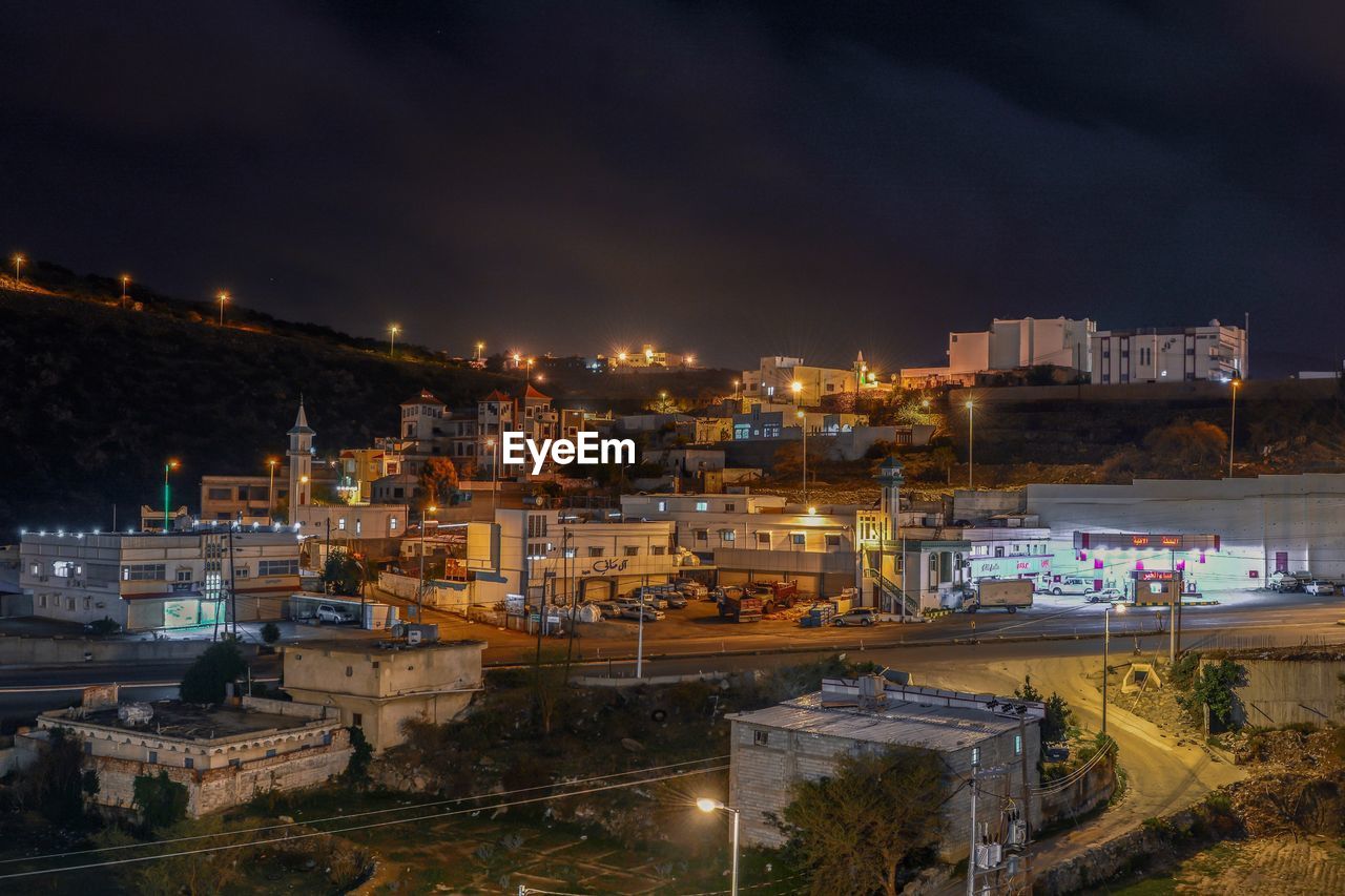 HIGH ANGLE VIEW OF ILLUMINATED CITY BUILDINGS AT NIGHT