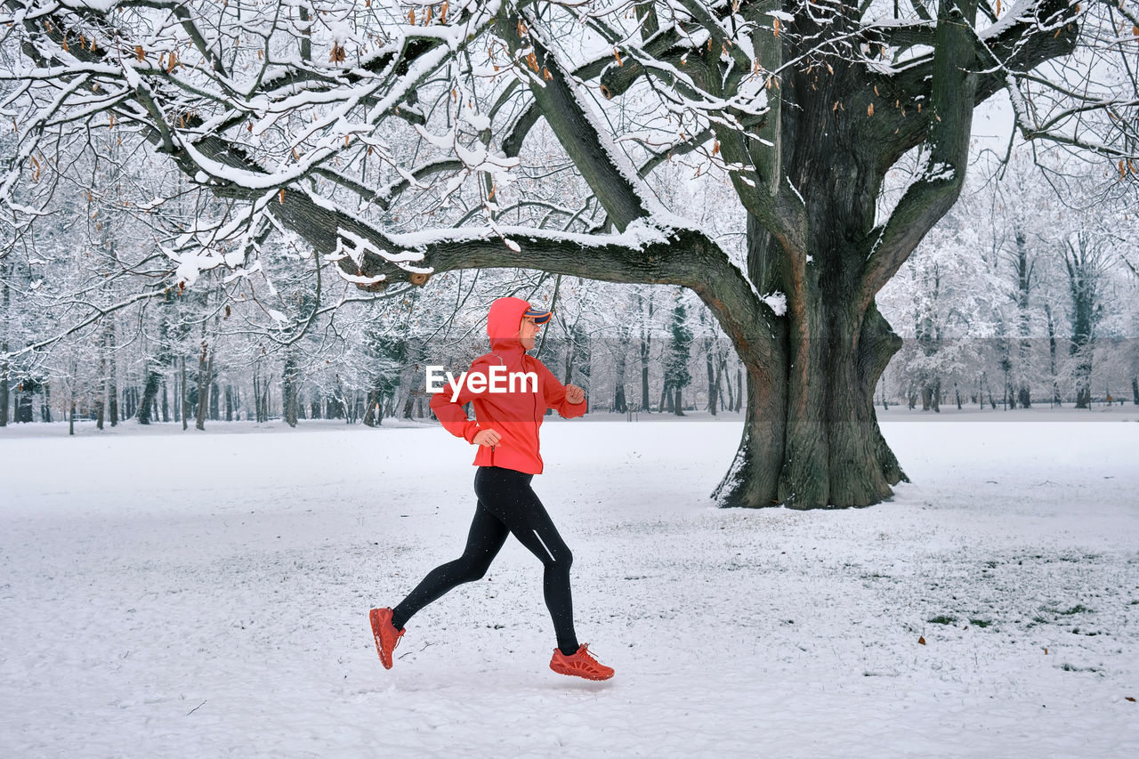 Running woman, girl runner on snow in park winter day. run, sport concept, leisure and freedom.