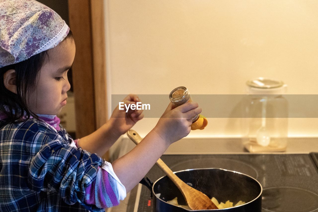 Side view of girl cooking food at home