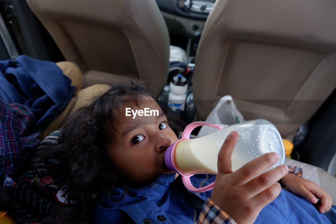 Portrait of girl drinking milk inside a car