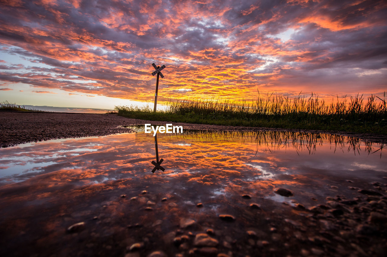 Scenic view of lake against dramatic sky during sunset