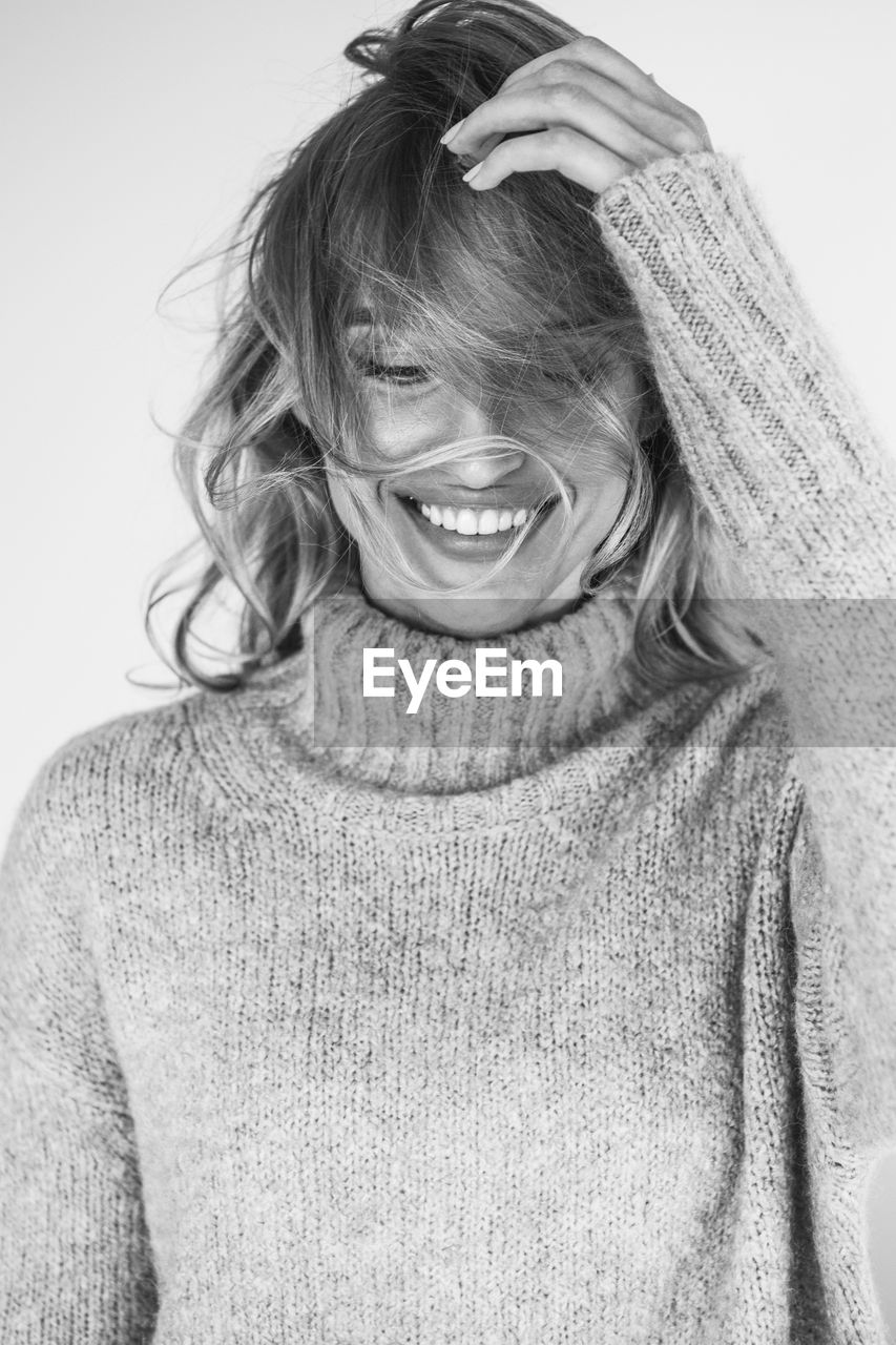 Close-up of smiling young woman against wall