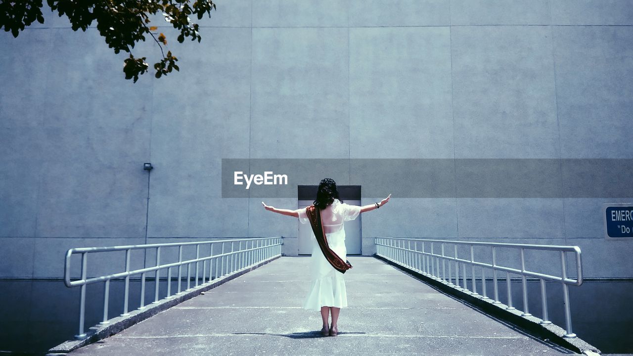 Rear view of man standing on railing against wall