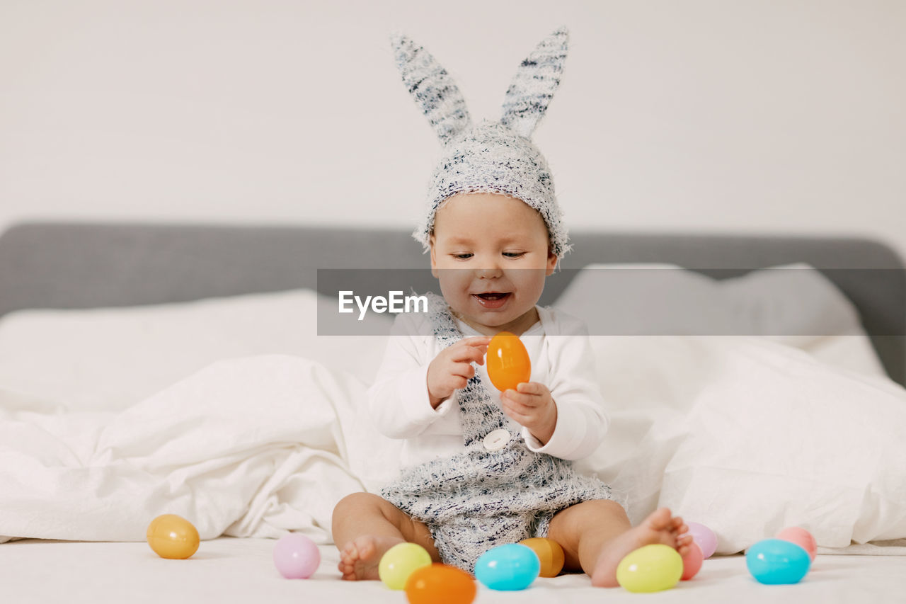 Cute child playing with toy while sitting on bed