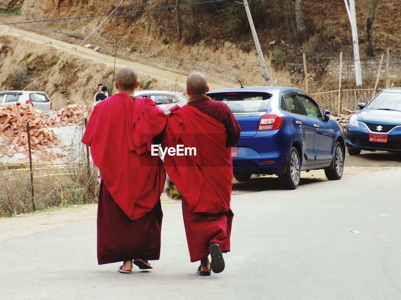 REAR VIEW OF PEOPLE WALKING ON ROAD AGAINST MOUNTAIN