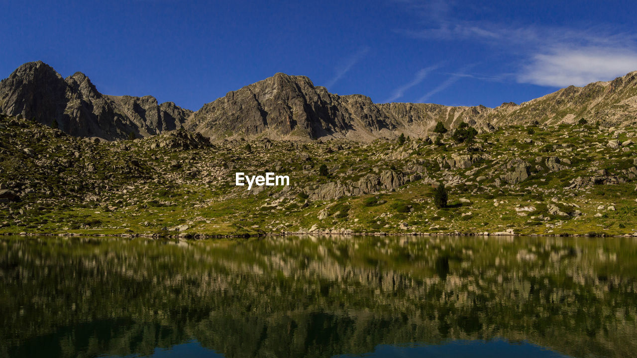 Scenic view of lake and mountains against blue sky