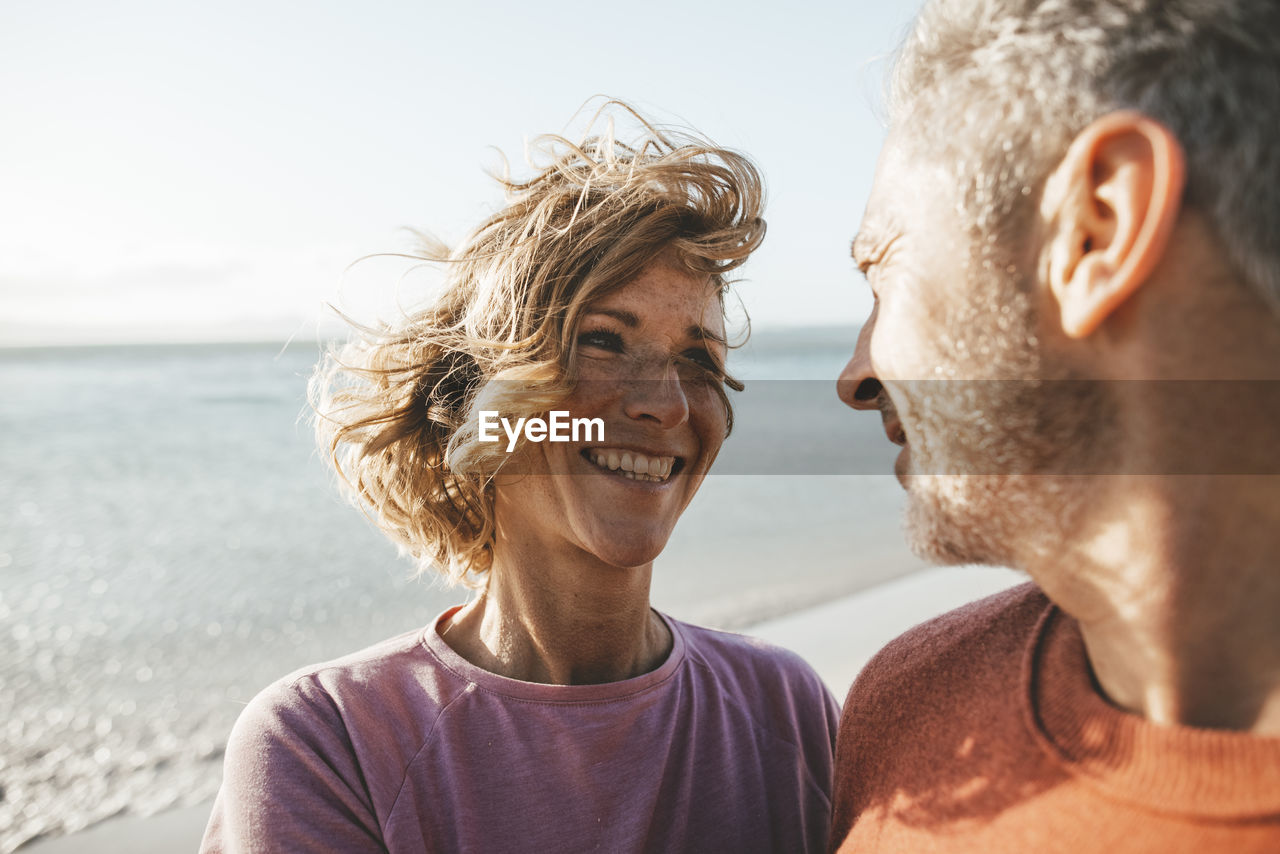 Happy blond woman looking at man on sunny day