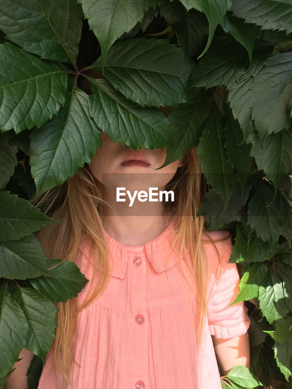 CLOSE-UP OF A GIRL WITH GREEN LEAVES IN BACKGROUND