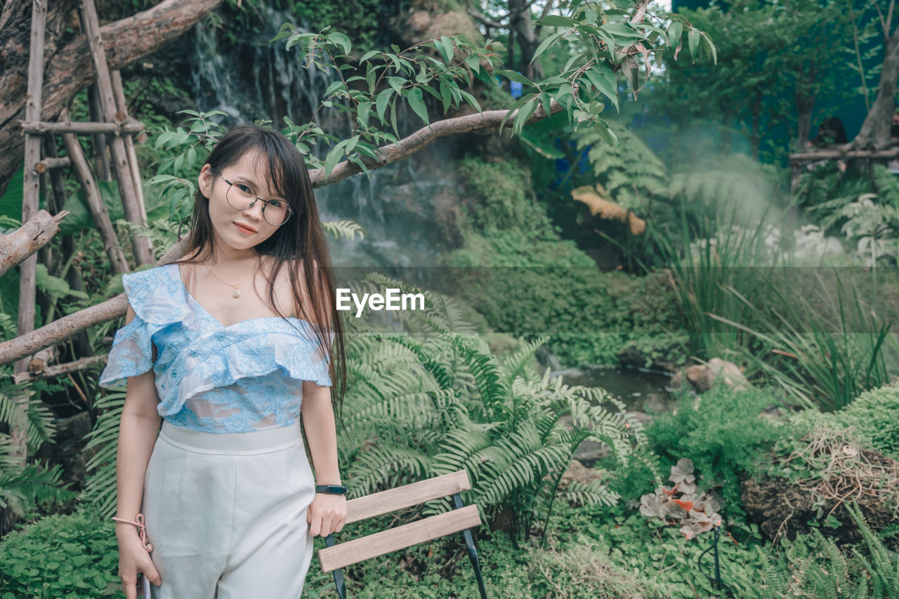 Portrait of woman standing against plants