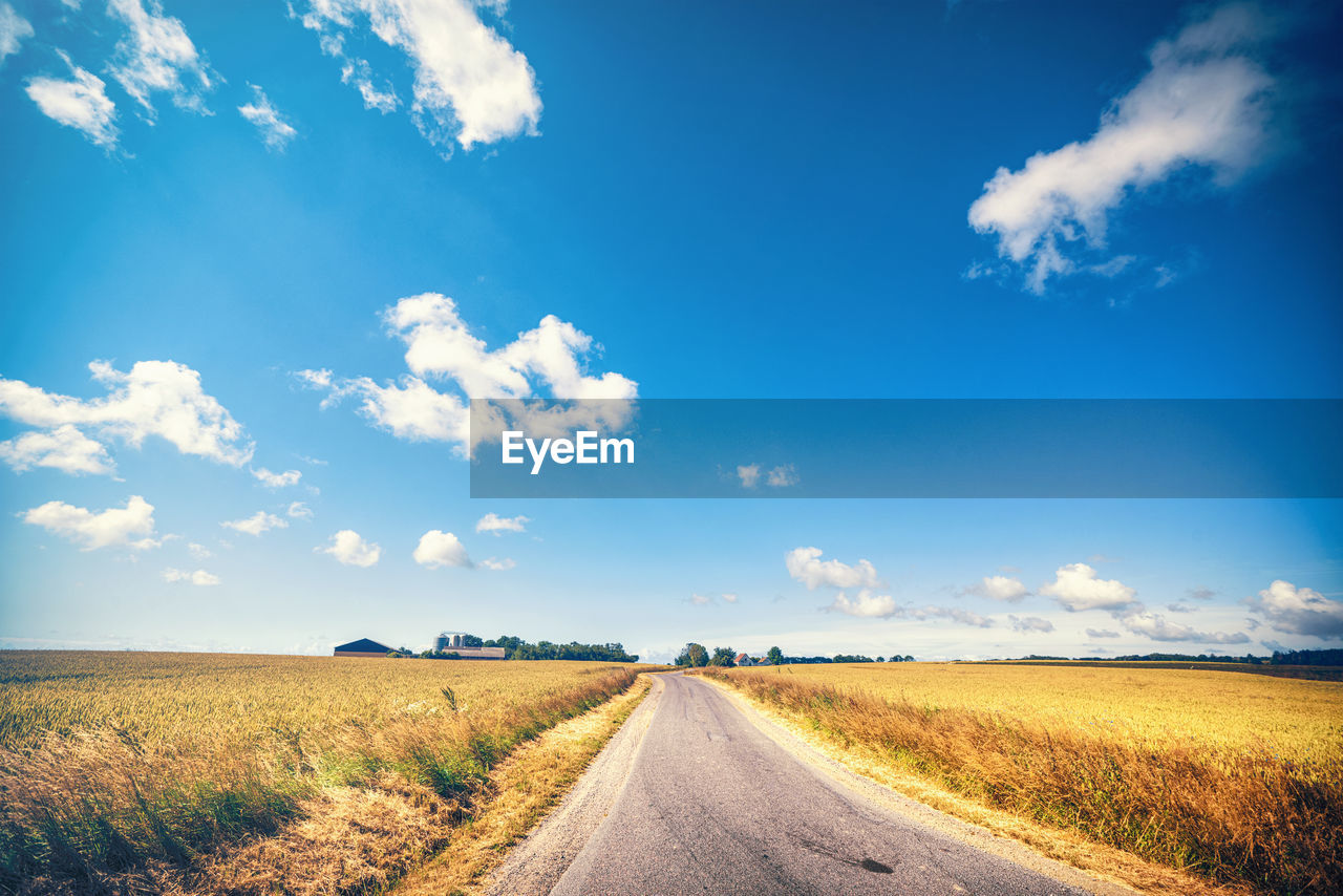 Road amidst field against sky