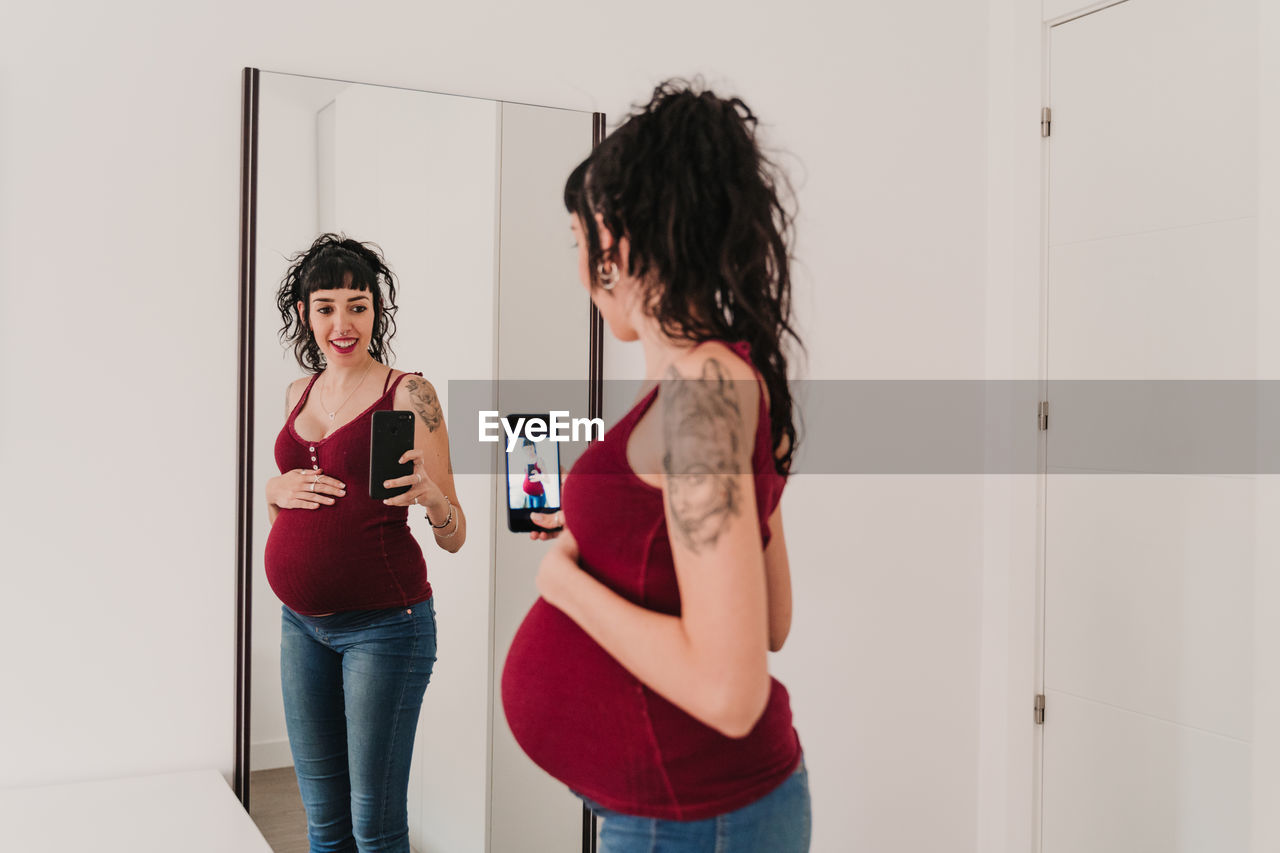 Pregnant woman photographing in front of mirror