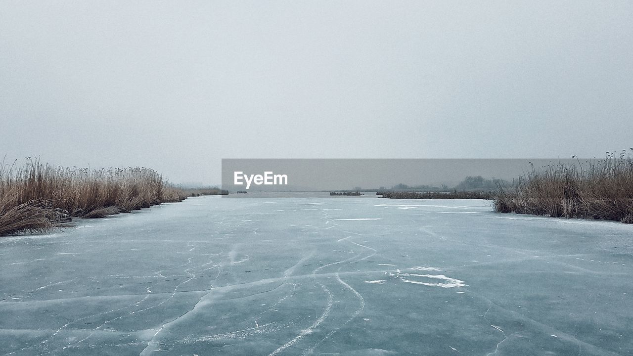 Scenic view of frozen field against clear sky