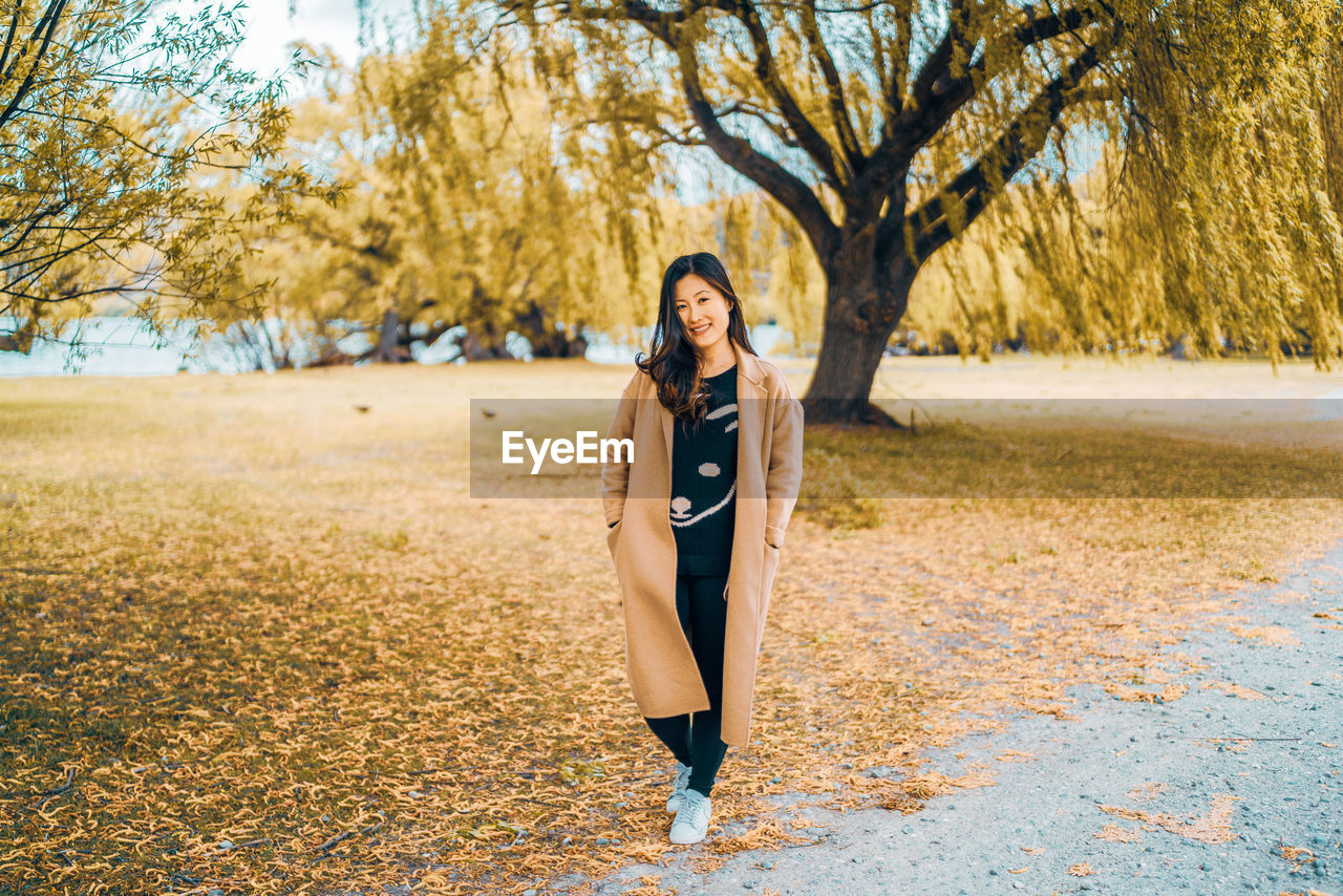 Portrait of smiling young woman on field during autumn