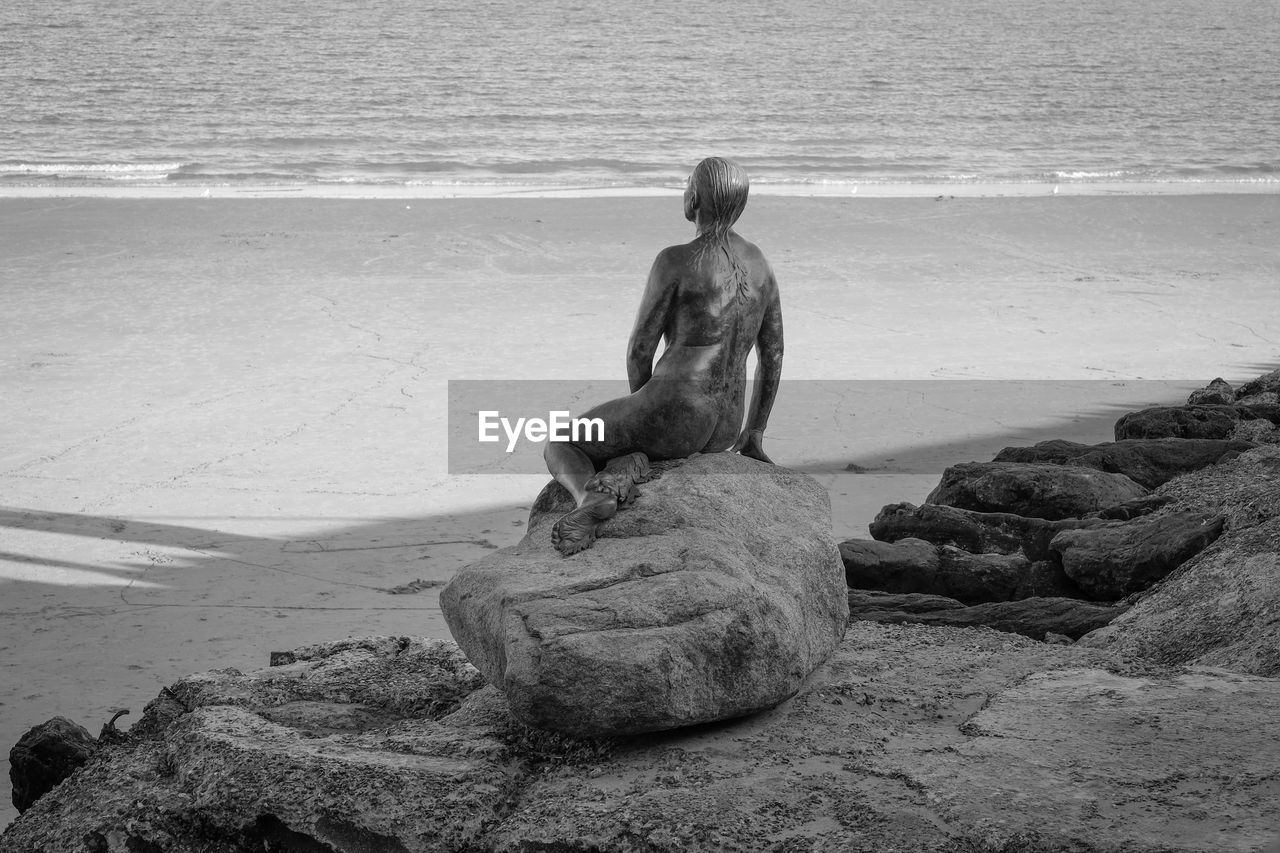 REAR VIEW OF STATUE ON BEACH